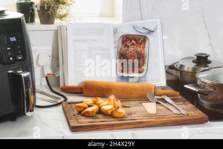 Ricettario aperto che mostra le istruzioni per preparare il pollo arrosto su un piano di lavoro della cucina Foto Stock