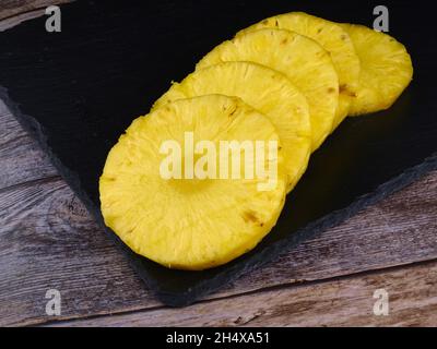 Ananas a fette su pietra scura. Tavolo in legno Foto Stock
