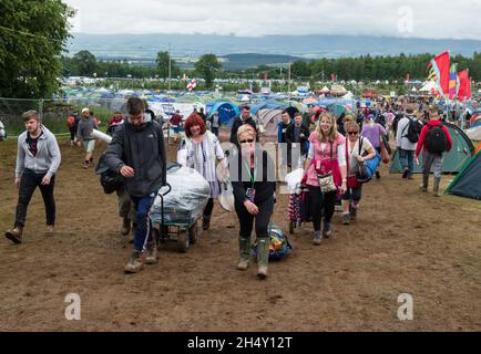 Festival Goers portando le loro attrezzature da campeggio attraverso il fango al Kendal Calling Festival a Lowther Deer Park il 08 agosto 2015 a Kendal, Regno Unito Foto Stock