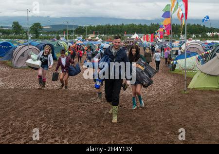 Festival Goers portando le loro attrezzature da campeggio attraverso il fango al Kendal Calling Festival a Lowther Deer Park il 08 agosto 2015 a Kendal, Regno Unito Foto Stock