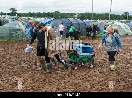 Festival Goers portando le loro attrezzature da campeggio attraverso il fango al Kendal Calling Festival a Lowther Deer Park il 08 agosto 2015 a Kendal, Regno Unito Foto Stock