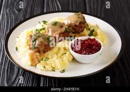 Cucina finlandese deliziose polpette con sugo di carne servite con purè di patate e marmellata di mirtilli da vicino in un piatto sul tavolo. Orizzontale Foto Stock