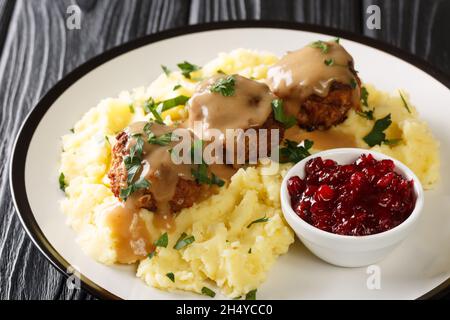 Polpette gustose con sugo di carne, purè di patate e marmellata di mirtilli in un piatto sul tavolo. Orizzontale Foto Stock