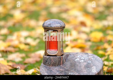 su una piccola lapide con foglie autunnali in sfondo sfocato Foto Stock