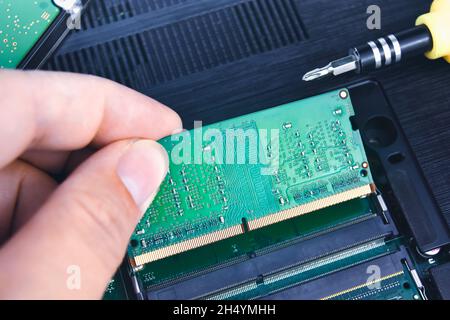 Un tecnico installa una RAM in un computer portatile (Random Access Memory) Foto Stock