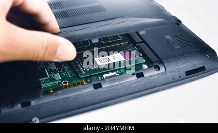 Un tecnico ispeziona la RAM di un computer portatile aprendo il coperchio (Random Access Memory) Foto Stock