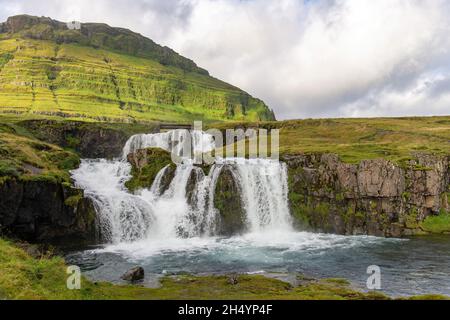 Vista ad angolo basso della cascata di Kirkjufell vicino a Grundarfjordur in Islanda situato vicino al monte Kirkjufell Foto Stock