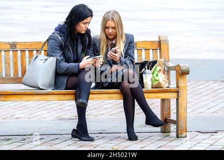 Dundee, Tayside, Scozia, Regno Unito. 5 novembre 2021. UK Meteo: Un giorno di novembre fresco e luminoso in tutta la Scozia nord-orientale con temperature che raggiungono i 12°C. Due giovani ragazze della Dundee High School seduti insieme per inviare messaggi di testo sui loro cellulari durante la pausa pranzo della scuola nel centro di Dundee. Credit: Dundee Photographics/Alamy Live News Foto Stock