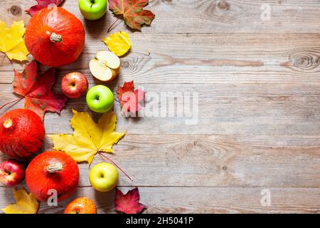 Il confine autunnale da mele, zucca e foglie cadute su un vecchio tavolo di legno. Concetto di giorno di ringraziamento. Zucca di ringraziamento con frutta. Frutta e vegeto Foto Stock