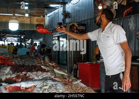 Non esclusiva: HURGHADA, EGITTO - 31 OTTOBRE 2021 - Un uomo lancia il pesce in un mercato del pesce, Hurghada, Egitto. Foto Stock