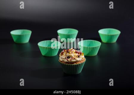 In silicone verde bakeware con un cupcake, primo piano su sfondo nero. Foto Stock