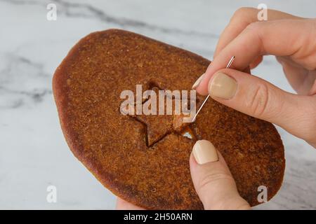 Kiev Ucraina - Ottobre 2021 giocando a Dalgona Coreano o Ppopgi caramelle a nido d'ape da Squid Game Challenge. Forma a stella. Caramelle di zucchero fatte in casa. Gioco non riuscito. Foto Stock