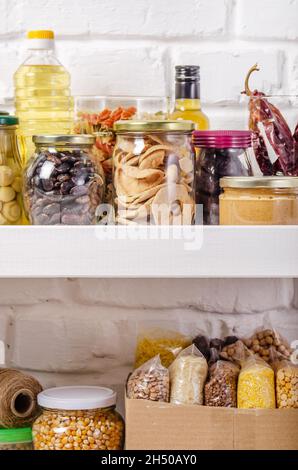 Set di alimenti non deperibili su ripiano dispensa su sfondo muro di mattoni Foto Stock