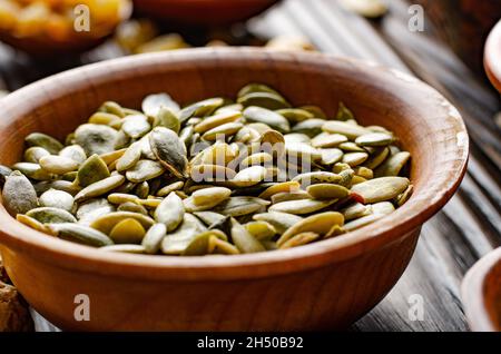 Semi di zucca sgusciata-Pepitas in ciotola di legno su cibo da tavola da cucina sfondo Foto Stock