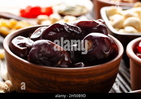 Disidratato datteri essiccati in ciotola di argilla su tavola di legno della cucina cibo sfondo Foto Stock