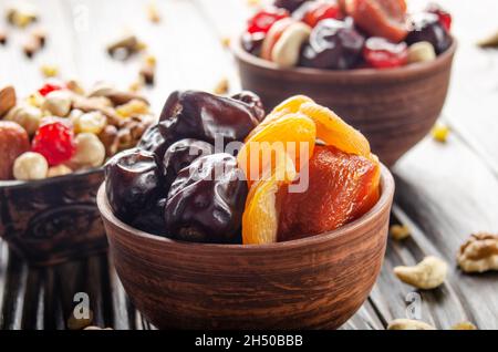 Datteri secchi e albicocche in ciotola di argilla su cucina di legno primo piano del tavolo Foto Stock