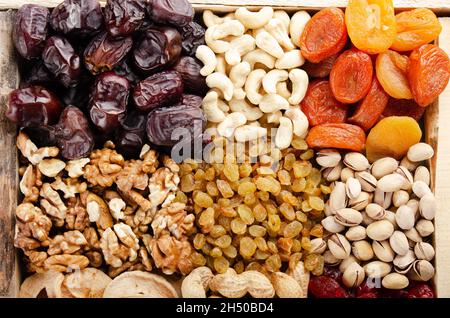 Vista piatta su frutta secca assortita e frutta secca in cassa di legno. Sano cibo vegetariano concetto Foto Stock