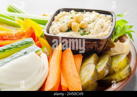 Vista a basso angolo su piatto di verdure con hummus condito con ceci e olio d'oliva Foto Stock