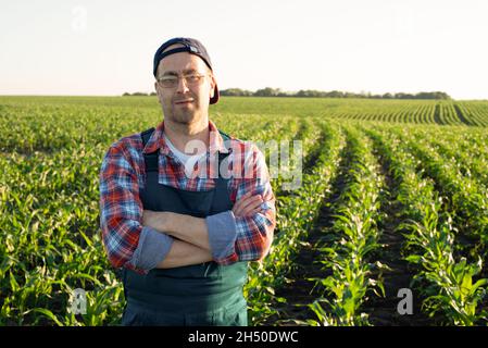 Uomo caucasico di mezza età sicuro soddisfatto contadino lavoratore con le braccia incrociate stand a campo di mais Foto Stock