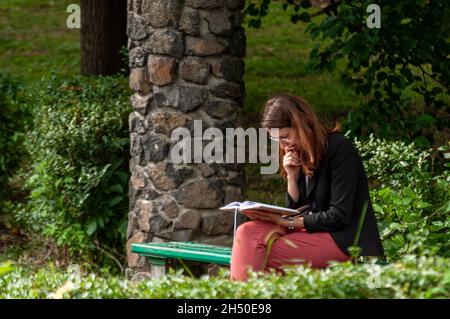 Timisoara, Romania - 1 giugno 2016: Donna che legge un libro in un parco. Persone reali. Foto Stock