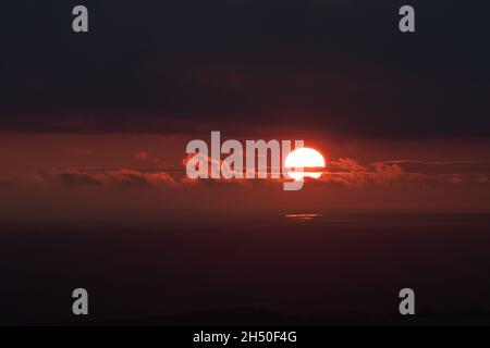 Tramonto Moody contro il cielo arancione scuro con il sole che si infrange attraverso le nuvole. Grandi aree di spazio vuoto per la copia o il testo Foto Stock
