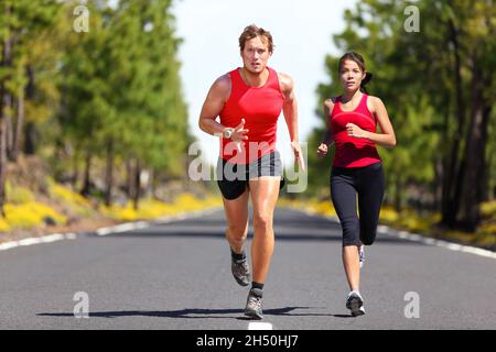 Fitness coppia di runners che fanno sport su strada all'aperto. Vita attiva uomo e donna jogging allenamento cardio in estate all'aperto natura. Asiatico Foto Stock