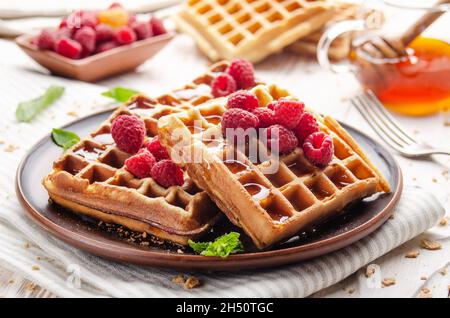 Waffle belgi croccanti fatti in casa serviti con lamponi e miele Foto Stock