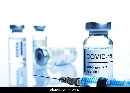 Flaconcino di vetro con etichetta di vaccino del coronavirus e closeup della siringa Foto Stock