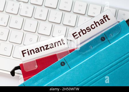 L'ufficio fiscale tedesco di parole e l'eredità può essere visto sulle etichette di un rosso e blu cartelle appese. Le cartelle sospese si trovano su un keyboar del computer Foto Stock