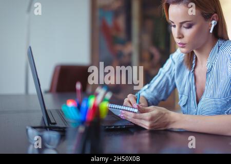 Giovane imprenditore focalizzato donna d'affari che fa appunti al portatile Foto Stock