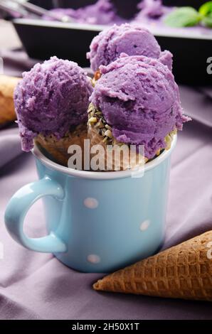 Coni wafer con BlackBerry icecream in tazza blu su tavolo da cucina in legno Foto Stock