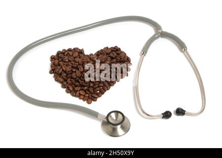 Stetoscopio e chicchi di caffè in forma cuore su sfondo bianco.concetto di malattia cardiaca e dipendenza Foto Stock
