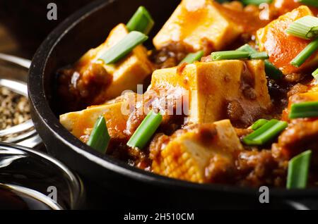 Mapo tofu in padella di ghisa con salsa di soia di erba cipollina tritata di maiale aglio e spezie di pepe di sichuan Foto Stock