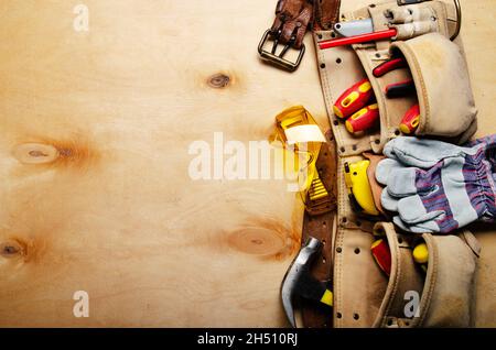 Cintura portautensili con attrezzi per falegnami e usura protettiva su compensato vista foglio piatto Foto Stock