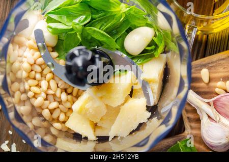 Ingredienti per la tradizionale salsa di pesto genovese italiana nel recipiente del robot da cucina. Vista piatta Foto Stock