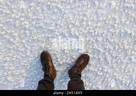 piedi maschi in stivali tra neve bianca Foto Stock