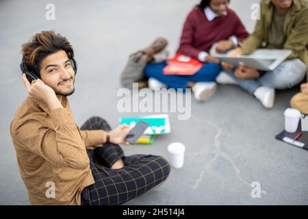 L'uomo indiano si siede sull'asfalto e guarda la macchina fotografica Foto Stock