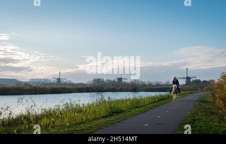 Una signora a cavallo con mulini a vento in lontananza, Kinderdijk, Paesi Bassi Foto Stock