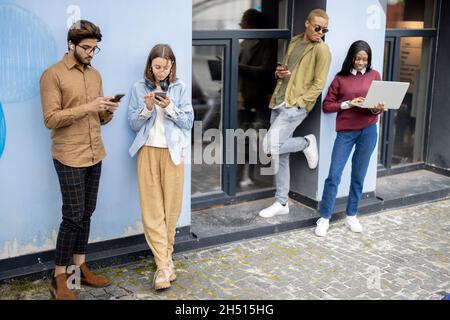 I giovani studenti usano i gadget nell'edificio dell'università Foto Stock