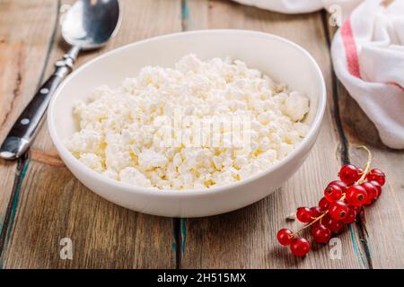 Formaggio fresco del cottage del contadino in una ciotola bianca su tavola di legno. Prima colazione salutare Foto Stock