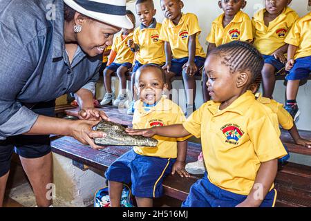 Johannesburg Sud Africa, Croc City Crocodile & Reptile Park, donna nera insegnante femminile, ragazzi ragazze studenti classe campo viaggio scuola materna uniformi Foto Stock