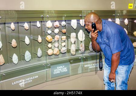 Johannesburg Sud Africa, University of the Witwatersrand Origins Center, museo preistorico Acheulean implementa Black man maschio ascolto audio tour Foto Stock