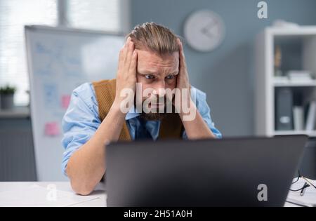 Uomo scioccato che guarda al computer Foto Stock