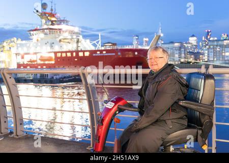 Anziana signora sulla mobilità scooter è venuto a Greenwich per visitare il RSS David Attenborough Barca ormeggiata nel Tamigi vicino Cutty Sark London UK Foto Stock