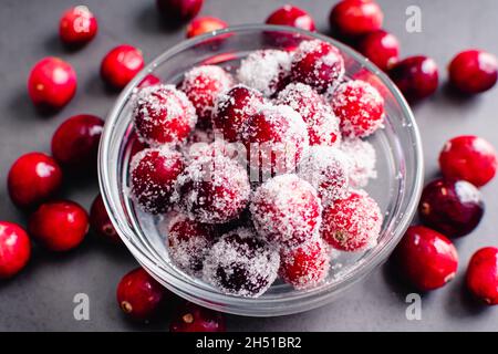 Mirtilli zuccherati in una piccola ciotola di vetro: Mirtilli freschi glassati con zucchero granulato Foto Stock