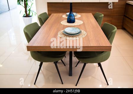 Moderna cucina interna, tavolo da pranzo in legno noce e sedie verdi Foto Stock