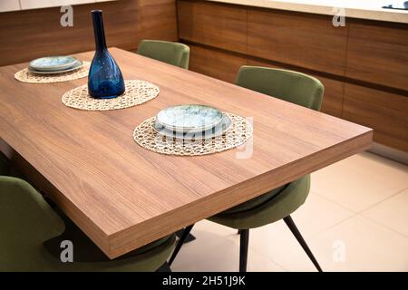 Moderna cucina interna, tavolo da pranzo in legno noce e sedie verdi Foto Stock