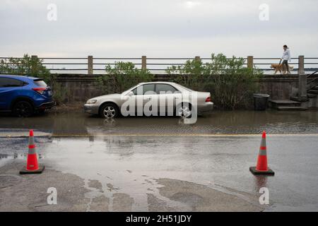 Charleston, Stati Uniti. 05 novembre 2021. Un camminatore del cane cammina lungo la batteria mentre l'acqua allaga porzioni di East Bay Street. Alcune parti del centro di Charleston hanno subito un secondo giorno di alluvione. La combinazione di un sistema di tempesta offshore e di una marea re insolitamente alta ha portato a diverse chiusure stradali in tutta la regione. La città sta soppesando i costi di realizzazione di un nuovo muro marino per combattere il crescente problema delle inondazioni. (Foto di Kit MacAvoy/SOPA Images/Sipa USA) Credit: Sipa USA/Alamy Live News Foto Stock