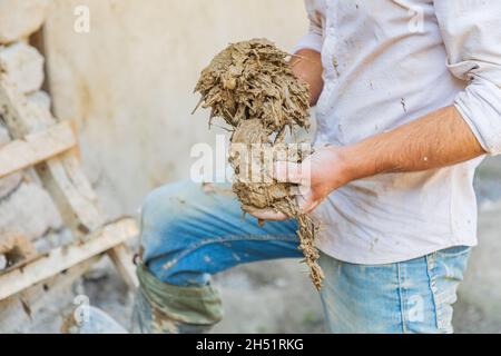 Mavzoley Rudaki, Provincia di Sughd, Tagikistan. Lavoratore che applica intonaco di fango ad una casa di pietra tradizionale. Foto Stock