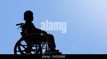 Silhouette di donna anziana disabile e dejected seduta in lei sedia a rotelle Foto Stock